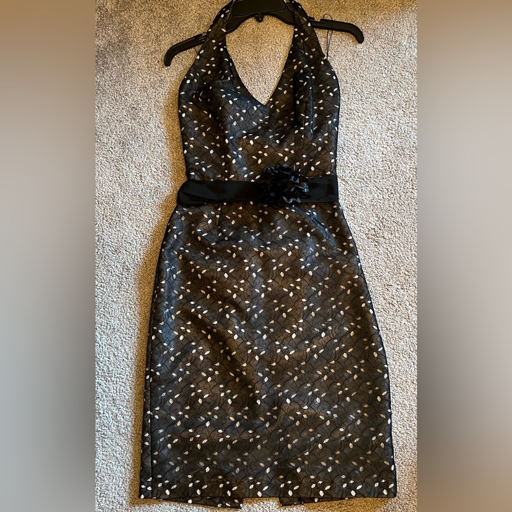 Black halter style party dress with design and silt in the back. Flower on belt.
